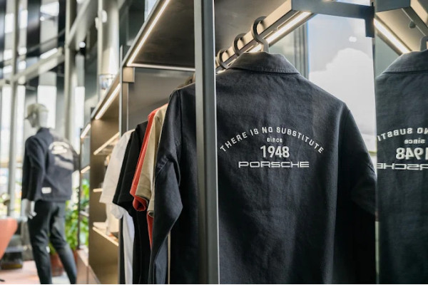 The Porsche clothing display with a dark jacket in the foreground and an illuminated shelving system.