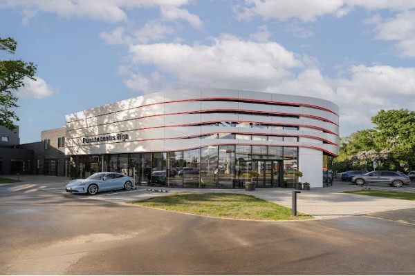 General view of the building of the Porsche Center in Riga with a rounded facade and extensive glazing.