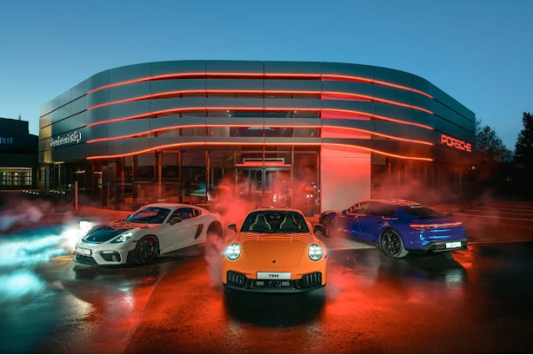 The facade of the Porsche Center in Riga in the evening with red light lines and cars.