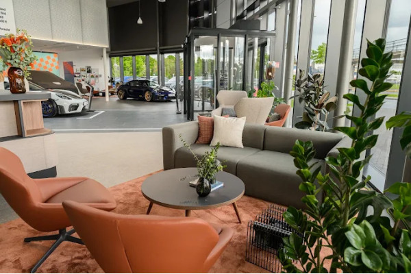 The customer lounge area with orange armchairs, a gray sofa and round tables.