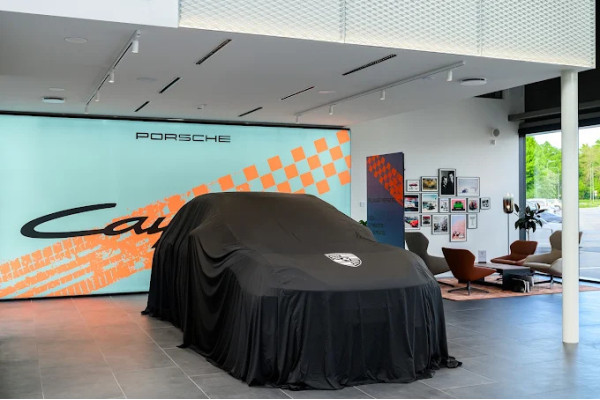Covered car in the presentation area in front of a large screen in the Porsche showroom.