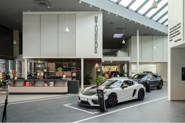 The Porsche Center Riga showroom with cars and a central furniture area.